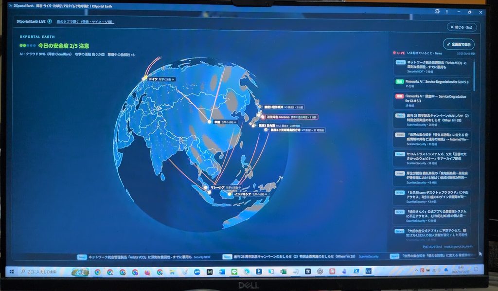 デスクのモニターにDXportal EarthのLIVE画面を表示した様子。中央に地球儀、右側に「いま起きていること」の一覧が並んでいる