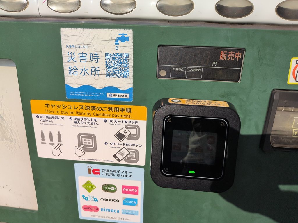 飲料の自動販売機に、二次元コード付きの「災害時給水所」のステッカーと、キャッシュレス決済の端末が並んでいる
